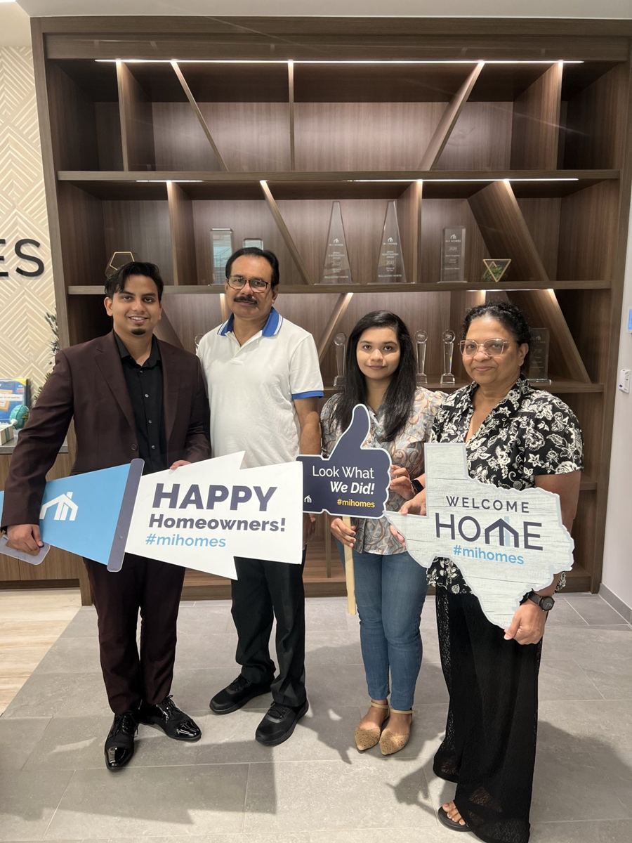 Suhail with a family holding Happy Homeowners and Welcome Home signs