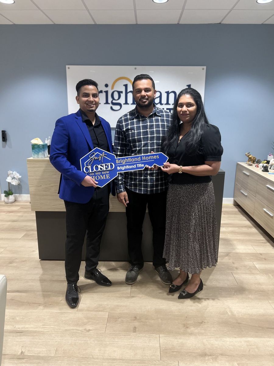 Suhail with buyers holding a Closed sign at the builder's office