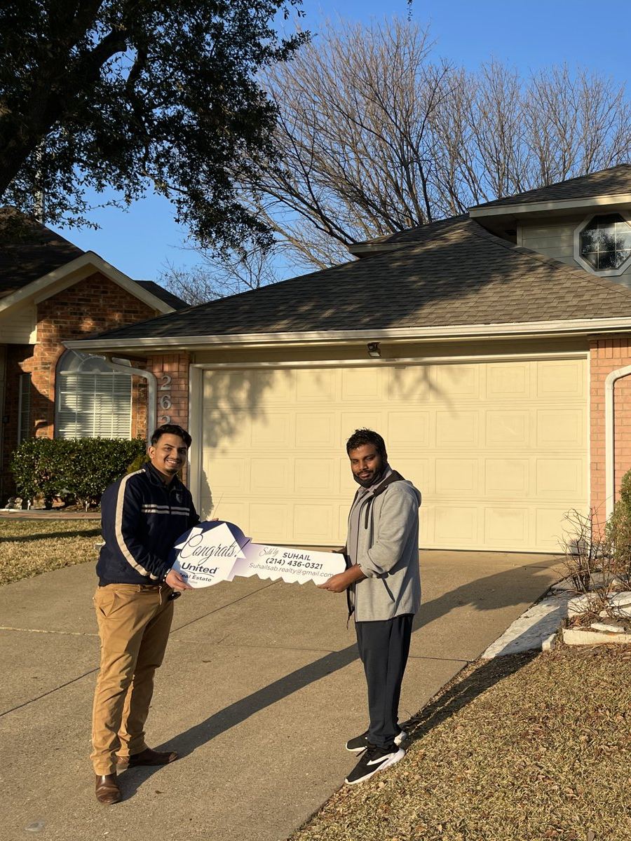Suhail handing a buyer the keys in front of his new home