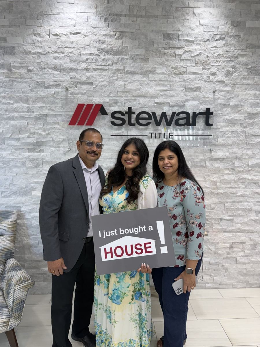 Family holding an I just bought a house sign at closing